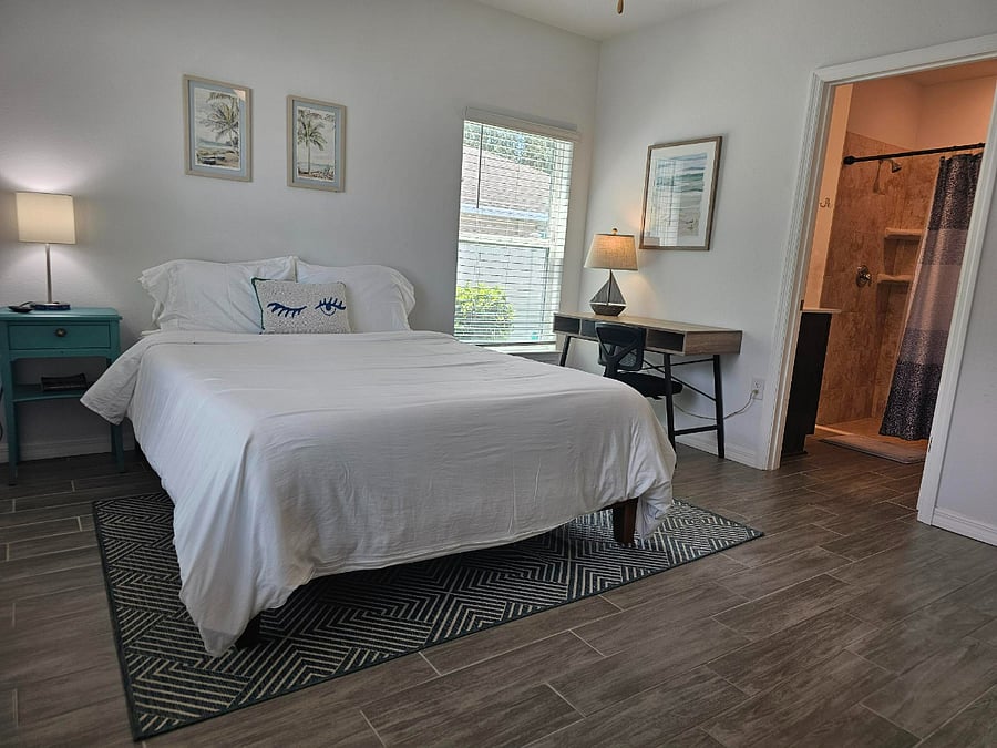Queen bed in primary bedroom with desk for remote work.