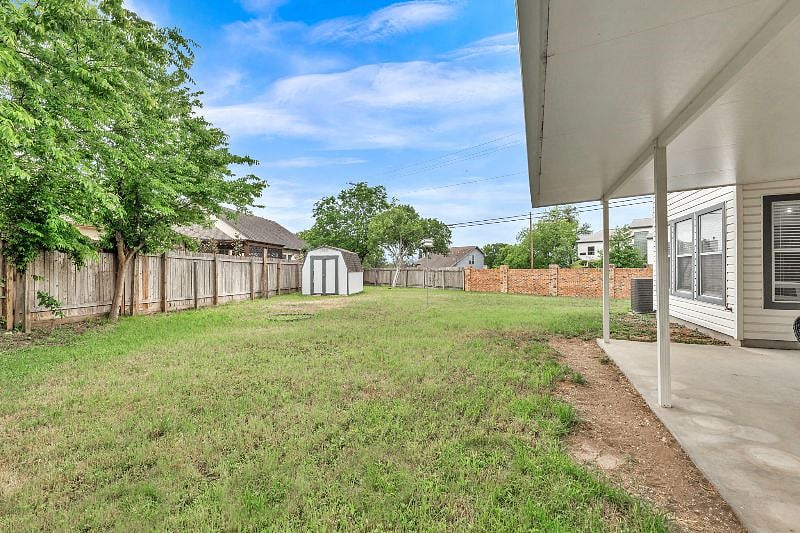 The backyard is covered in grass and surrounded by trees.