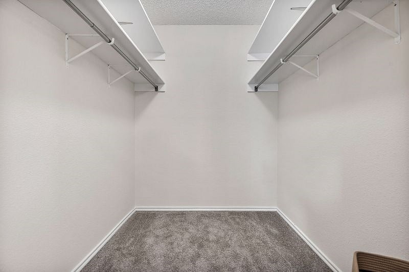 Walk-in closet in the secondary bedroom features hanging racks and storage shelves.