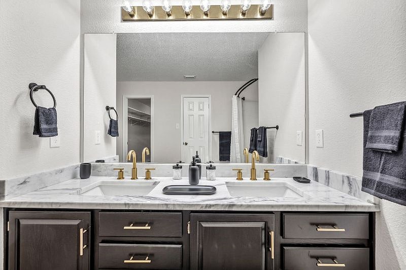 Brushed brass faucets with double sinks in the master bathroom.