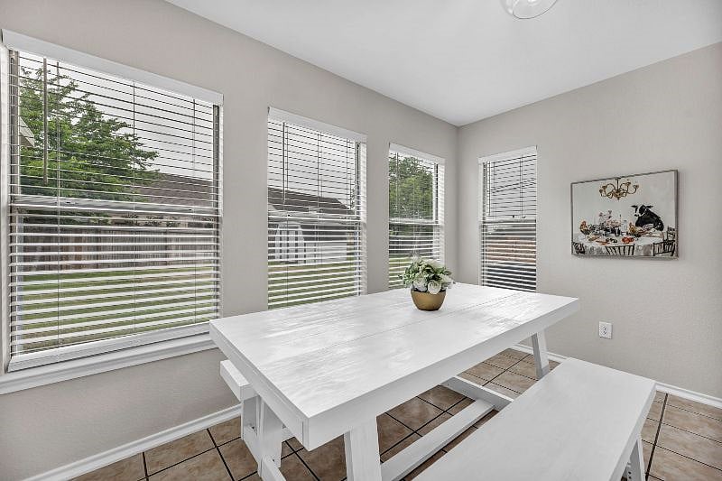 Charming dining area surrounded by windows and natural light as well as a hanging light.