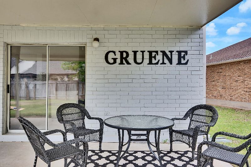 Covered backyard patio features outdoor seating/ dining area.