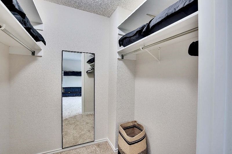 Walk-in closet in the third bedroom with additional pillows for guests. Hangers and laundry basket provided.