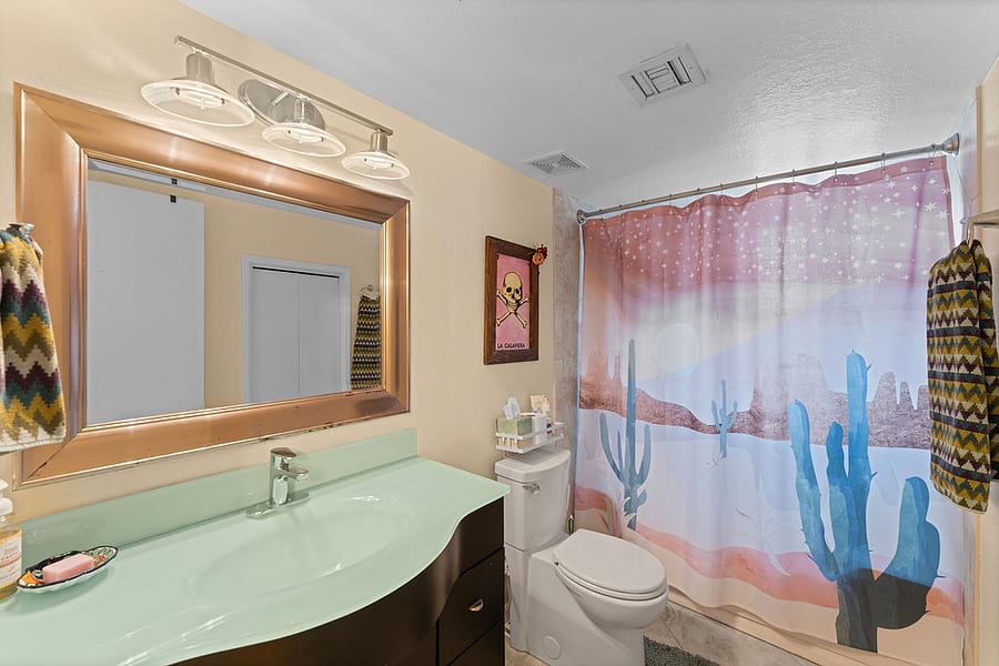 Spacious private bathroom with glass countertop, plenty of storage and water softener.