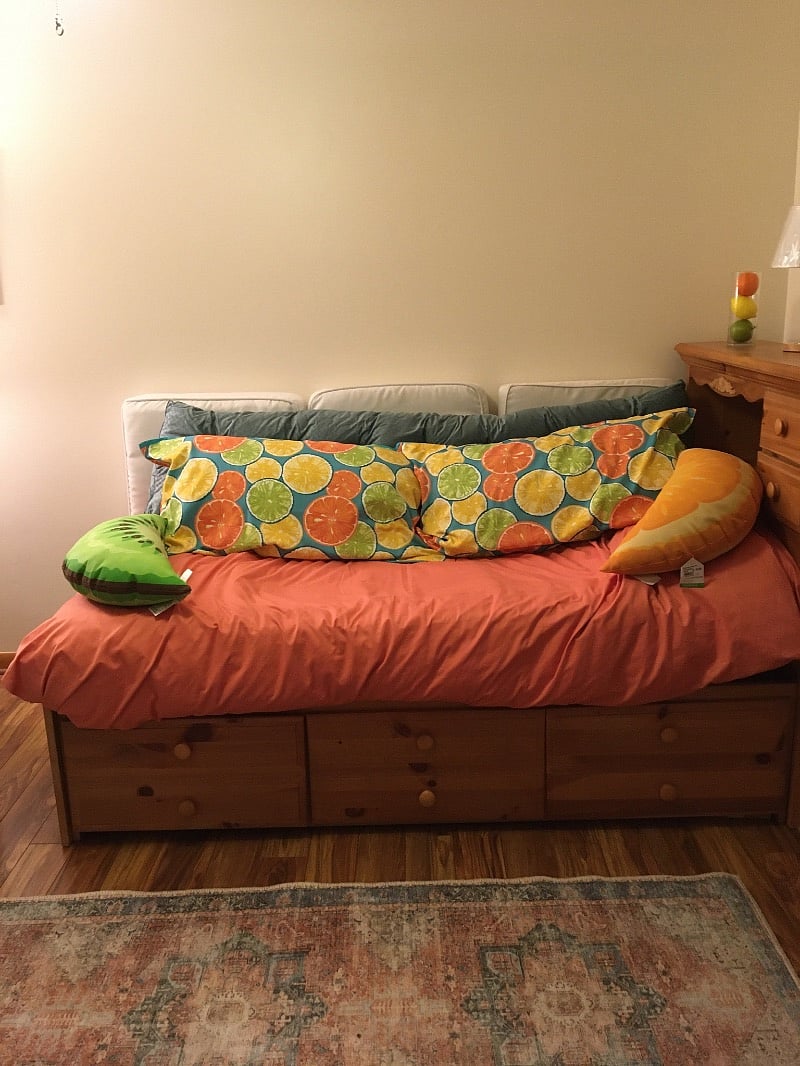 Cozy daybed made up as a couch in bright, cheerful lounge/kitchenette to be used as a private kitchen and living room.