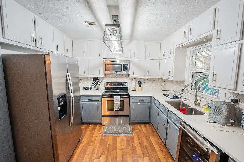 Fully equipped kitchen featuring stainless steel appliances, ample white cabinetry, and rich hardwood floors for comfortable home cooking.