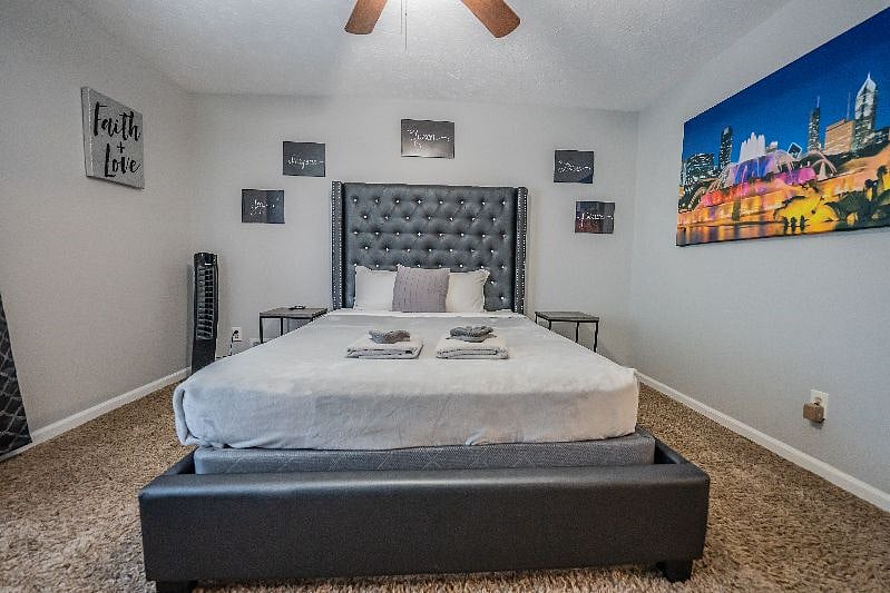 Comfortable bedroom with a plush upholstered headboard, fresh linens, and tasteful city-skyline wall art.