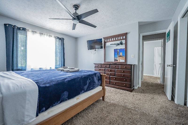 Restful bedroom with cozy bedding, a dresser for storage, and a large window letting in plenty of natural light.