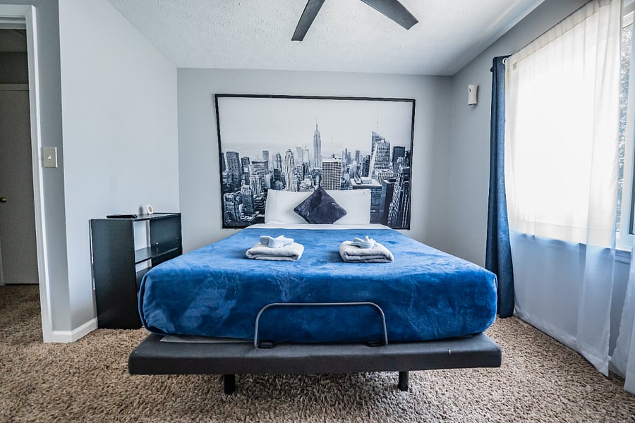 Stylish bedroom with a queen bed, fresh towels provided, and striking black-and-white New York skyline artwork.
