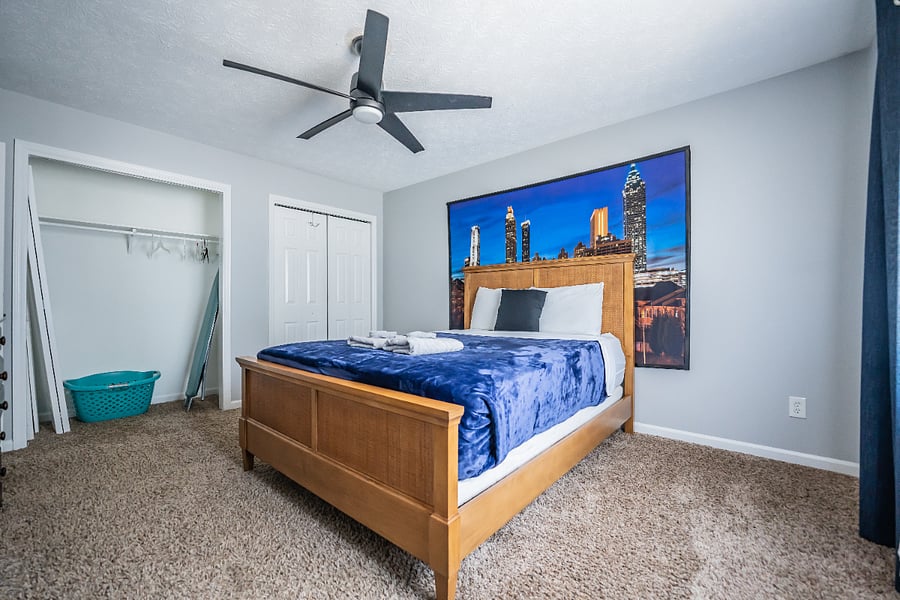 Welcoming bedroom with a solid wood bed frame, cozy bedding, and a vibrant city-skyline canvas.