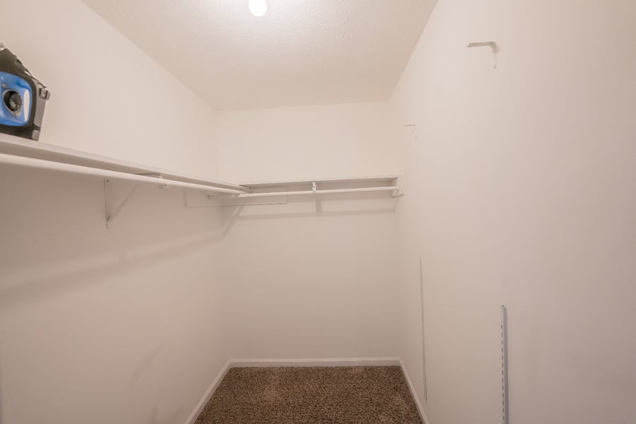 Generous walk-in closet with built-in shelving and carpeted flooring for convenient storage during longer stays.