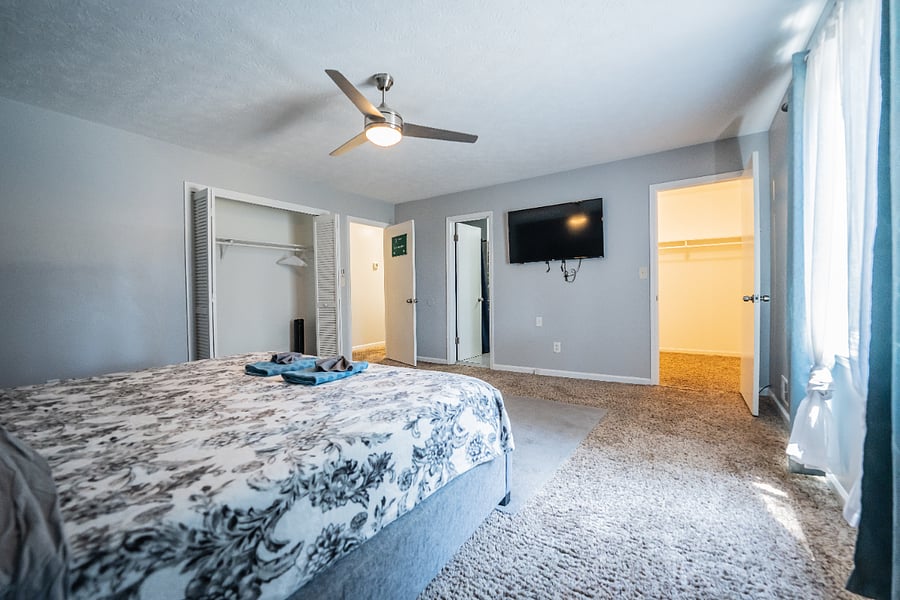 Comfortable bedroom with patterned bedding and a ceiling fan, conveniently located near the closet.