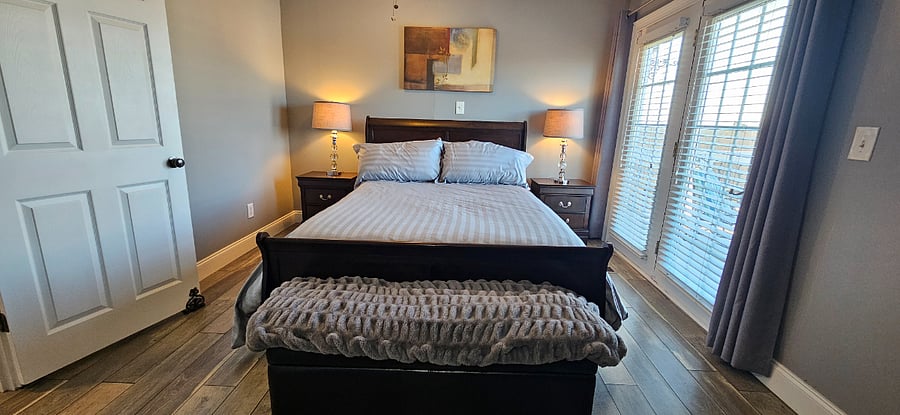 Master bedroom with the balcony door closed. Comfy bed and dresser. Room darkening curtains.