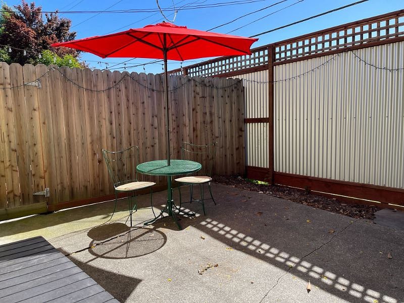 Back patio with iron bistro table for 2 with umbrella and twinkle lights.