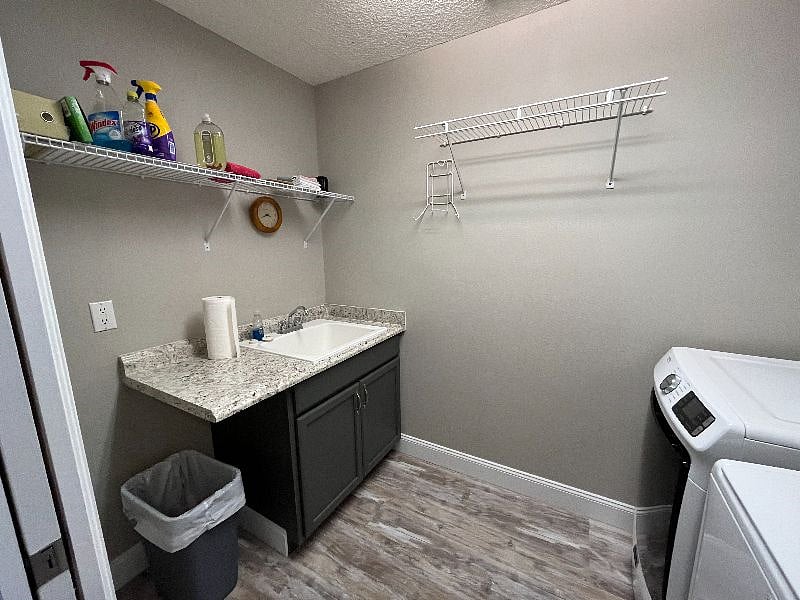 Laundry room is across foyer from kitchen and has a sink and storage