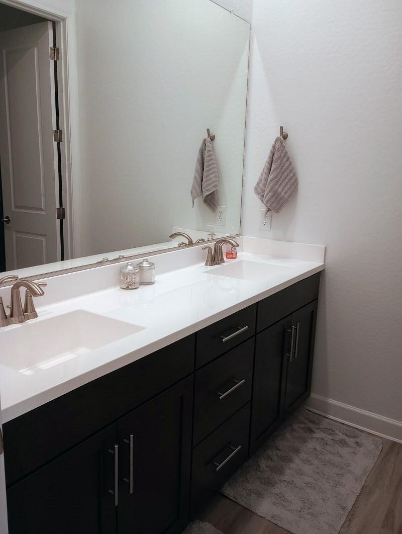 2nd bathroom with dual sinks and door between sinks and stool/tub area