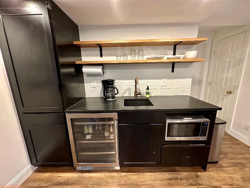 Kitchenette with microwave, working sink, and beverage fridge. Also includes an electric kettle, hot plate and toaster oven. Full size fridge located in the laundry room.