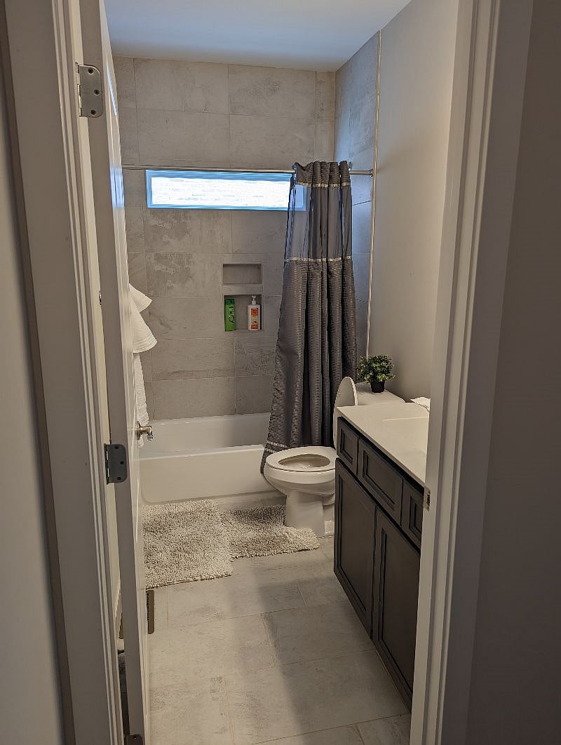 Full bathroom, next to middle bedroom, and across from laundry room