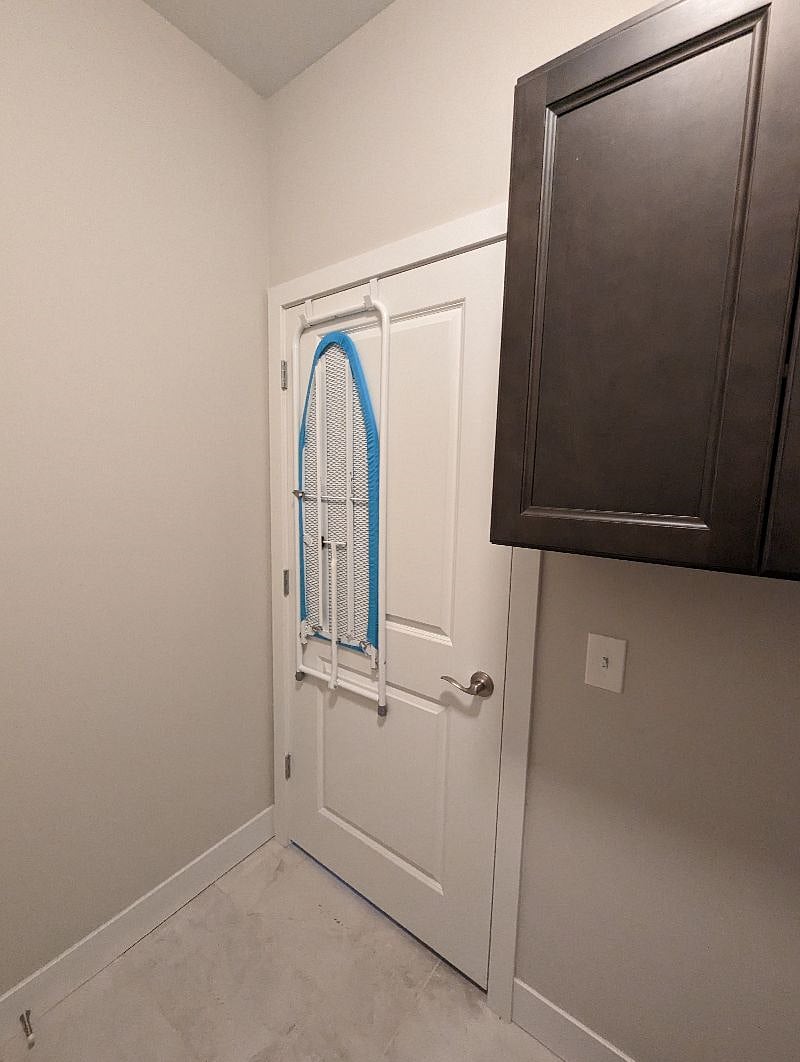 Ironing board on back of door in laundry room. Irons stored in cabinets. First aid kit stored in cabinets.