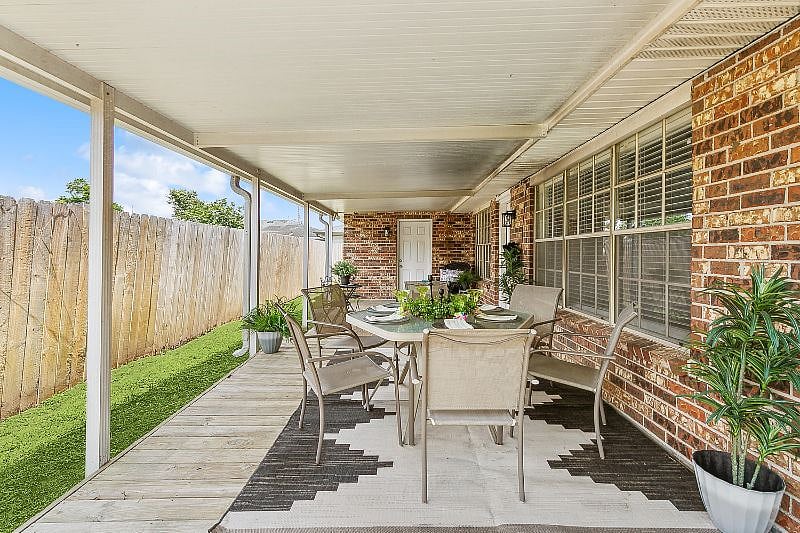 Beautiful covered patio with privacy fence and large outdoor patio table and barbecue pit.