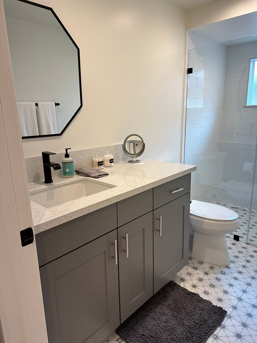 Walk in shower has nicely tiled floor, a roomy vanity and quartz counters!