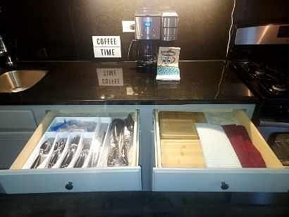 Upper drawer featuring silverware and cutting blocks and towels.
Coffee machine on counter.