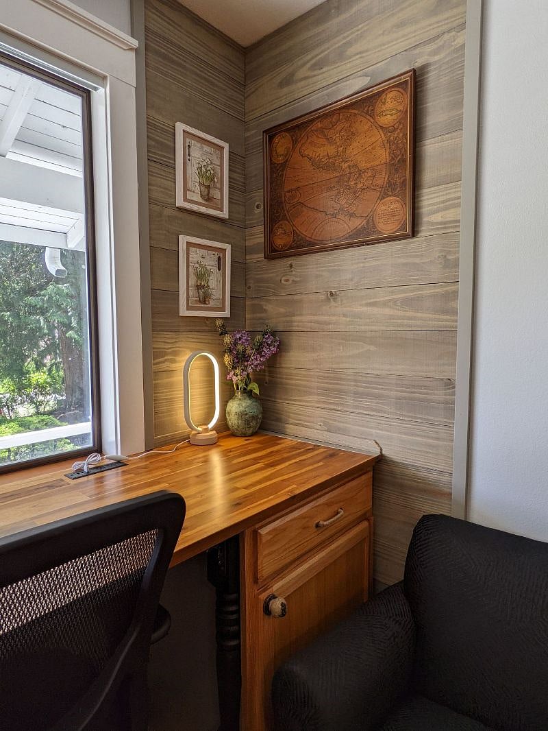 A desk, with a vase of flowers and many cute pictures.