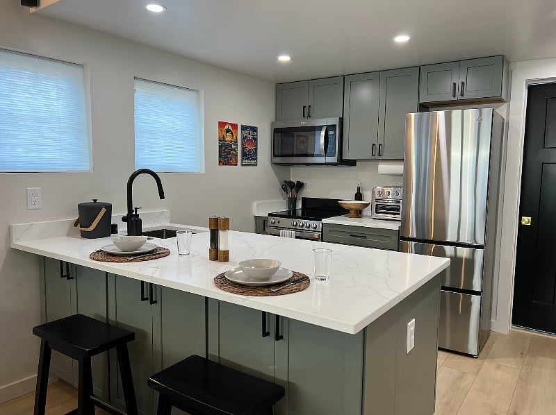 For a small house you'll have an enormous kitchen counter + workspace. Dine-in or work from the kitchen. There are cabinets facing the living room for extra storage, too