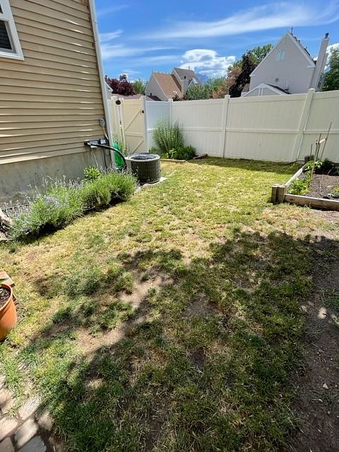 Fully fenced backyard with lawn and garden beds.