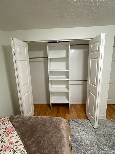 Closet with shoe shelves, a double bar on one side, and a bar for longer items on the other side.