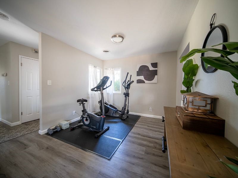 Mini indoor gym featuring exercise bike, elliptical, and small weights.