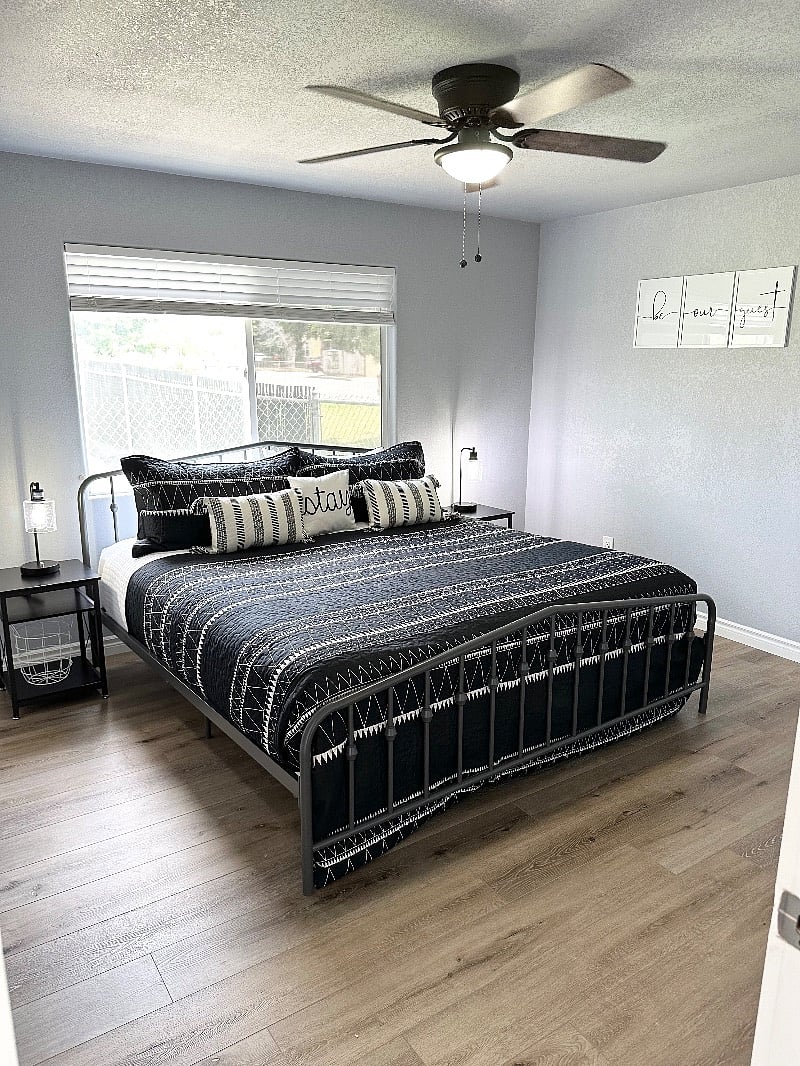 Master bedroom with king size bed, ceiling fan, digital alarm clock, nightstands, closet, and smart TV.