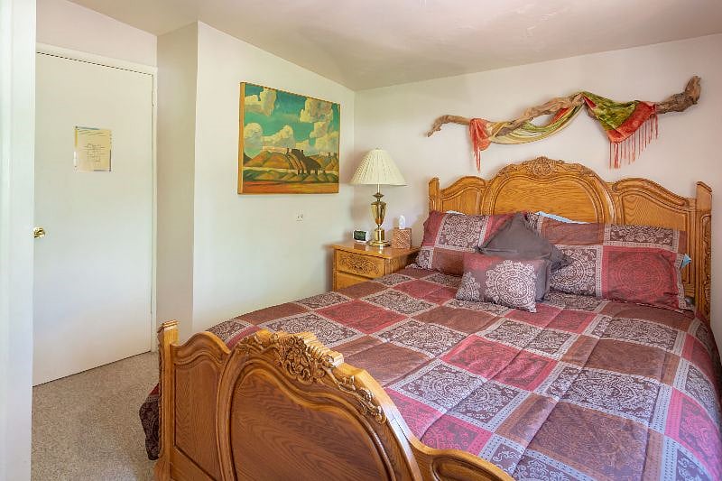 The east bedroom has a new queen bed, large dresser, closet for hanging clothes and a large mirror. There's pine trees and shady garden out the window.