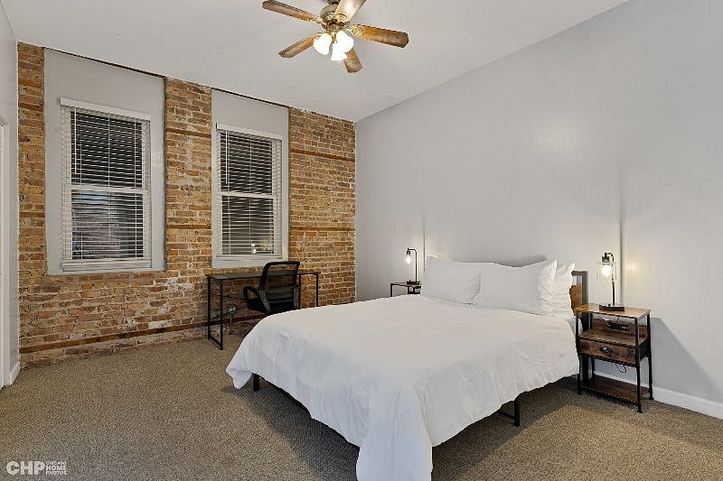 1st bedroom showing the desk, a queen size bed, and bedside tables with lamps