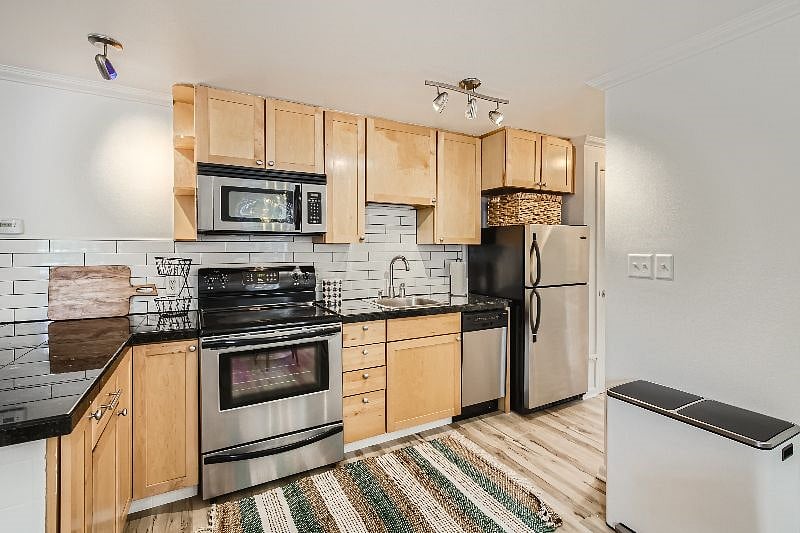 The kitchen features sleek granite tile countertops, modern subway tile backsplash, stainless steel appliances, & all the kitchen tools needed for your extended stay. There is also a full-sized pantry for extra storage.