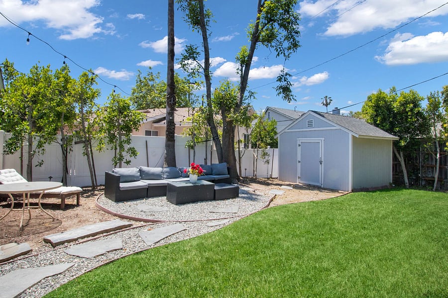 Large backyard: Newer fence, outdoor seating, grass area for dogs.