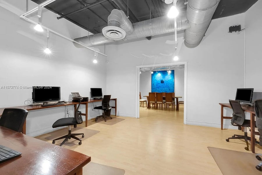 Business center with multiple computers, printers/scanners and conference table open to residents.