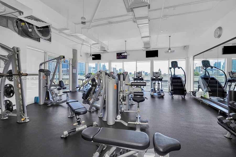 Gym with pool and cityscape views equipped with free-weights, squat rack, multiple machines, bikes, treadmills, stepper, medicine balls, kettle bells, yoga mats and more!