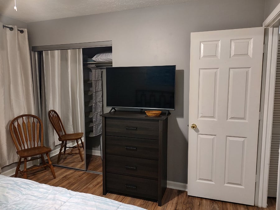 Primary bedroom with king sized bed, tv, and mirrored closet doors.