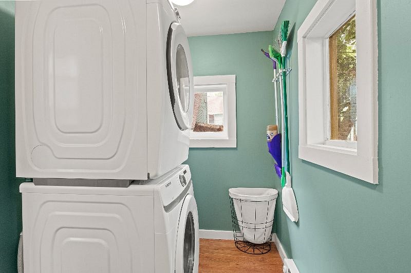Laundry room view featuring stacked Samsung washer and dryer with cleaning supplies nook and storage