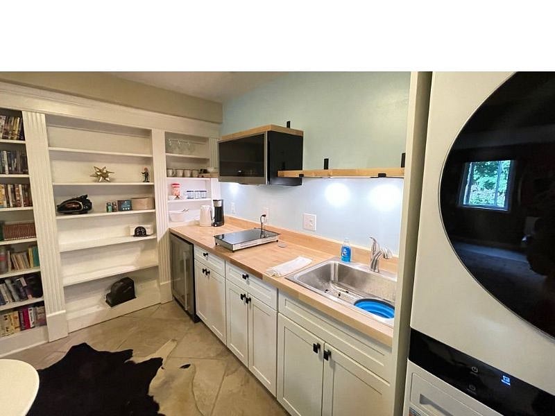 Full Kitchenette with shelving above. Books and media storage shelves are in the backgound.