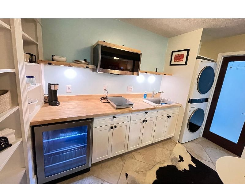 Kitchenette with sink, microwave, cooktop, frig, and washer/dryer.