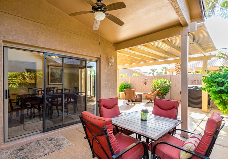 Outdoor covered patio area off of the dining room.  Table with seating, additional chairs and a gas gril.