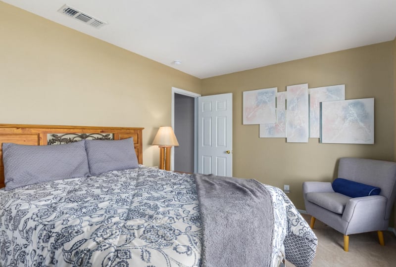 Bedroom with queen sized bed.  Comfortable seating,   dresser with mirror and bedside table with lamp.