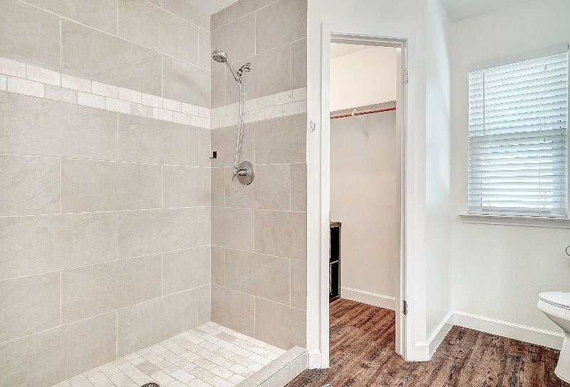 Newly renovated tile shower with high pressure Waterpik shower head in primary bathroom