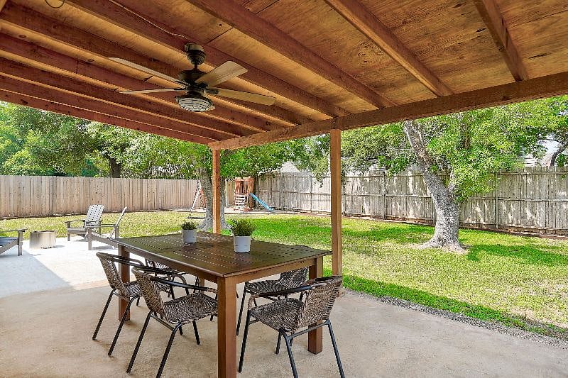 Expandable wooden patio table and woven chairs seat 6-8 people under the covered patio