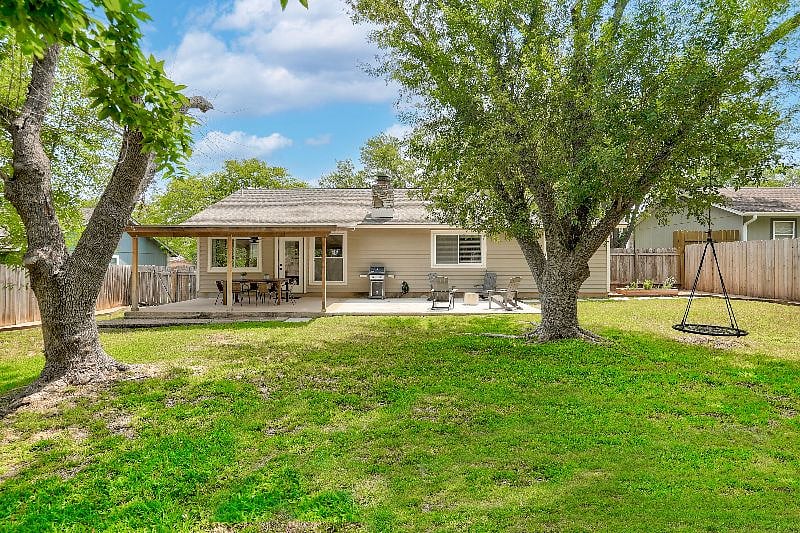 Large landscaped backyard with swing, play set, and herb garden