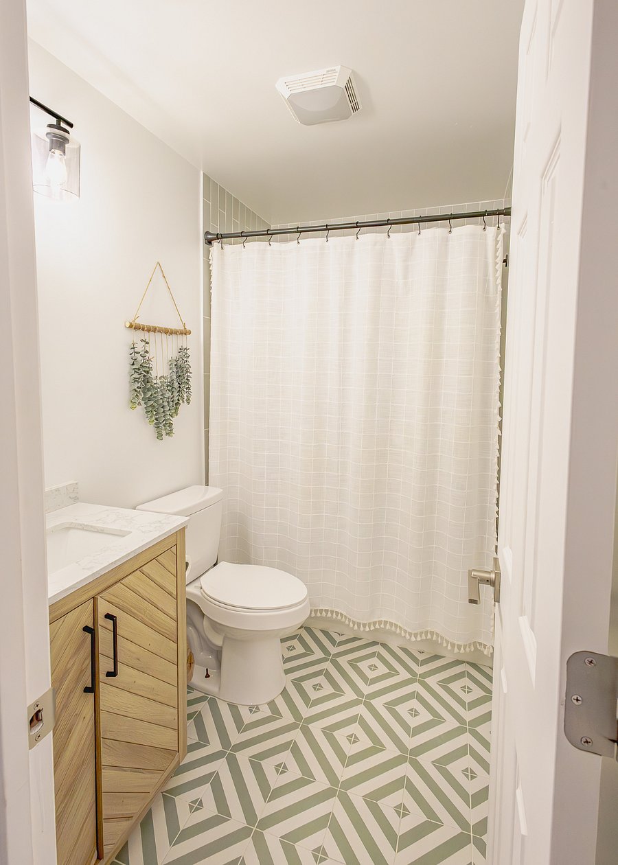 Full bathroom centrally located between both bedrooms with ample storage and geometric tile floor.