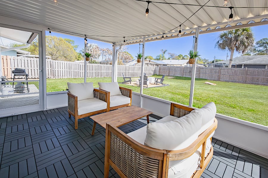 Screened lanai with string lights and teak seating. Ideal for morning coffee or quiet evenings after work.