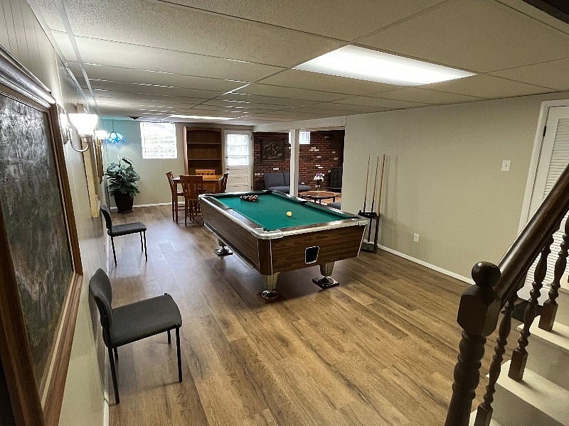 Walkout basement that includes pool table, bar height table, sitting area, and 32" TV with Amazon Firestick.